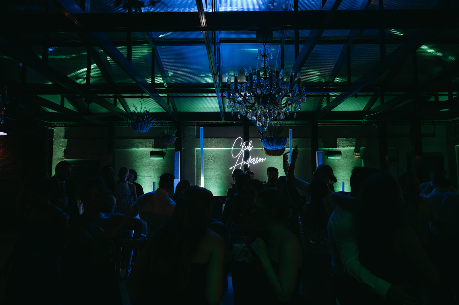 Wedding guests dancing beneath blue and green Venue Lighting