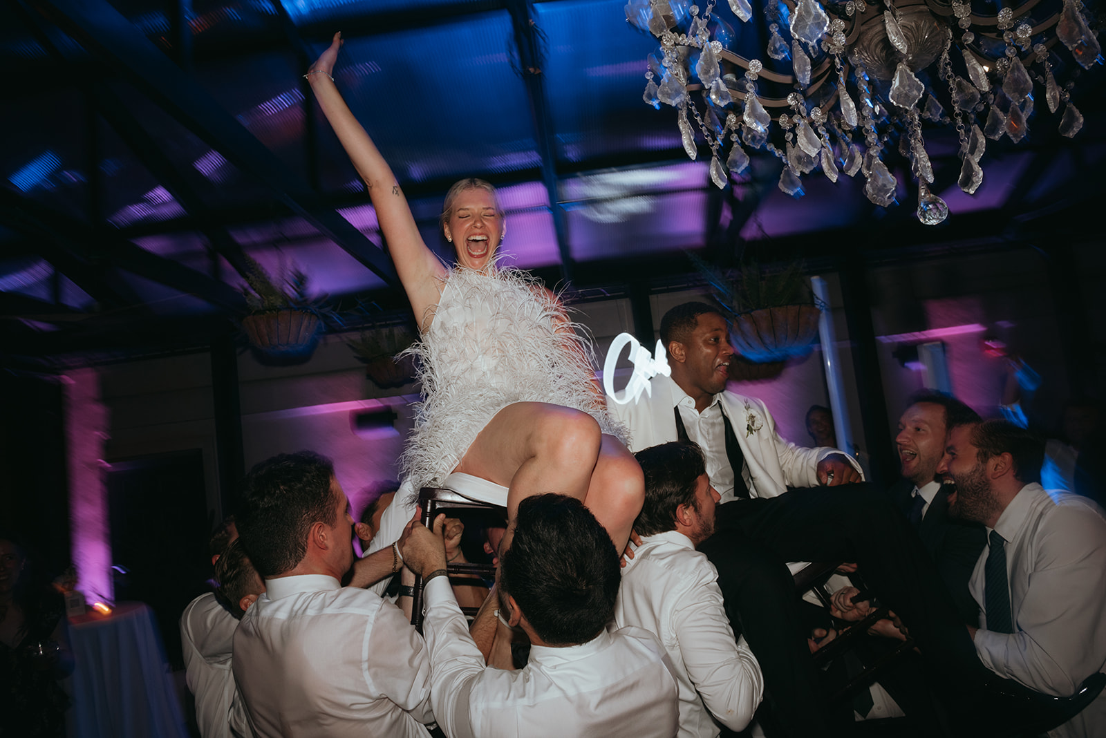 Newlyweds lifted on chairs by guests on a lively wedding dance floor